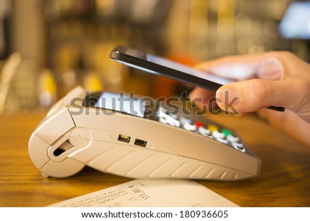 Woman paying with NFC technology on mobile phone, restaurant, shop
