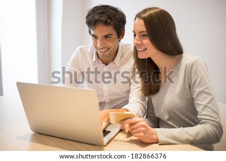 Couple using credit card to shop on line. Laptop. Indoor desk