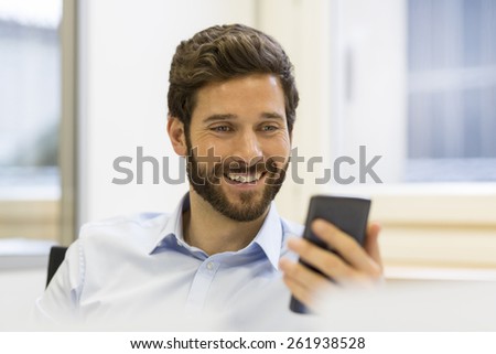 Hipster man in office. Typing text message on mobile phone