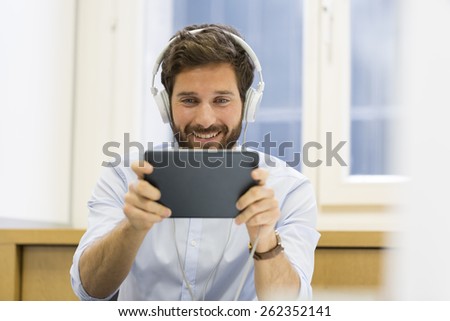 Man in office withe tablet pc and headphones