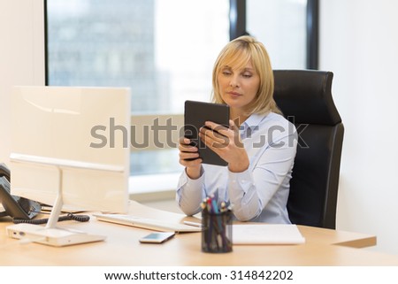 Middle aged business woman using tablet pc at office