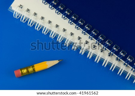 Very small pencil with memo-pads on blue desk