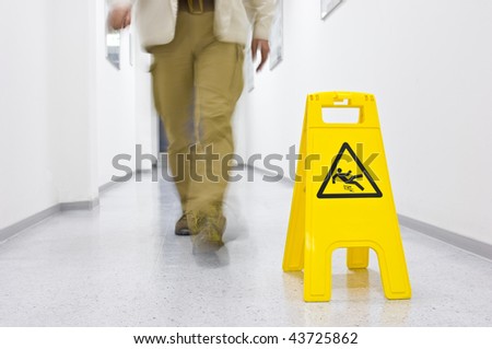 Warning sign for slippery floor, person walking down the floor