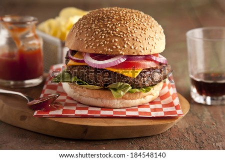 Classic deluxe cheeseburger with lettuce, onions, tomato and pickles on a sesame seed bun