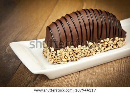 Chocolate coated bananas cake with nuts on wooden table