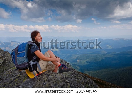 Hiker with backpack sitting on top of the mountain and looks into the distance.Freedom concept. Autumn mountain travel.