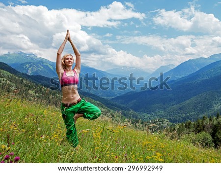 Young slim woman makes yoga poses on the mountains
