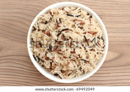 Close up view of cooked variety of rice sorts in bowl - basmati and indian black on wooden background