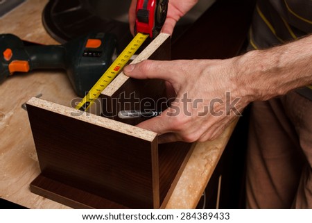 Hands furniture maker with a tape measure.