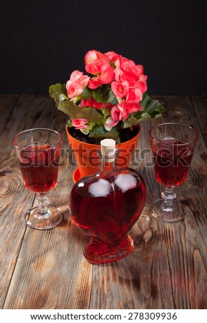 Bottle with red wine and flower on a wooden table