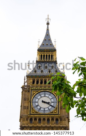 Big Ben from an unusual angle with foliage partly obscuring the clock face.