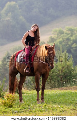 Young girl with long hair sitting on a horse breed Quarter Horse