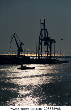 cranes in the port during the sunset. Silhouette of cranes and boat in the harbor