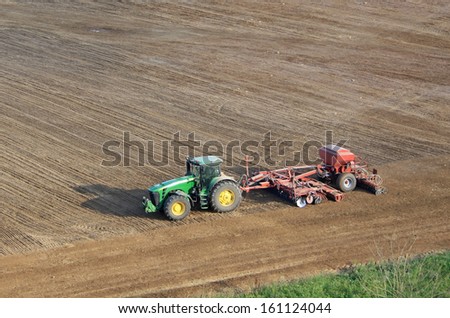 MOLODECHNO, BELARUS - AUGUST 27, 2013: John Deere tractor is working in the field on August 28 in Belarus. John Deere is an american company and leading manufacturer of agriculture machinery.