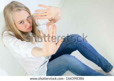 Scared Young Woman holding her hands up to say Stop