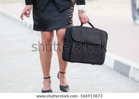 Businesswoman\'s legs, cigarette and a briefcase.Fast modern life!