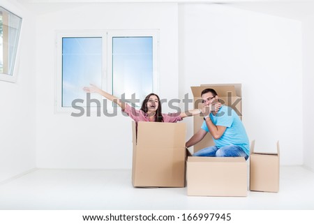 Portrait of beautiful,smiling woman sitting with man in a empty cardboard boxes in new home
