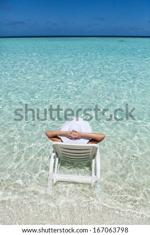 Young woman resting in a deck chair at the  tropical beach