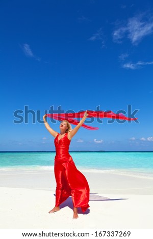 Woman wearing red dress on the tropical beach and holding a red sarong ,copy space