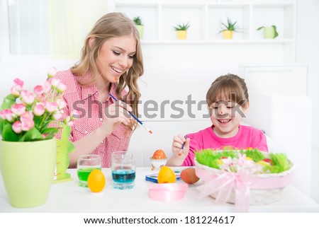Sisters with a toothy smile coloring Easter eggs in a domestic room