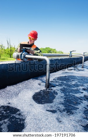 An engineer controlling the quality of water , aerated activated sludge tank at a waste water treatment plant