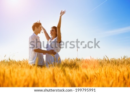Happy young couple enjoying in the wheat field, summer season. Sunset light, flare light, copy space