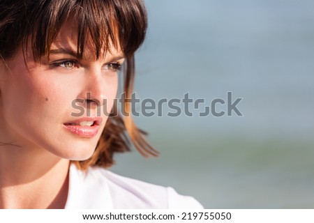 Portrait of young, beautiful, caucasian woman, head shot, seascape in the background.Copy space