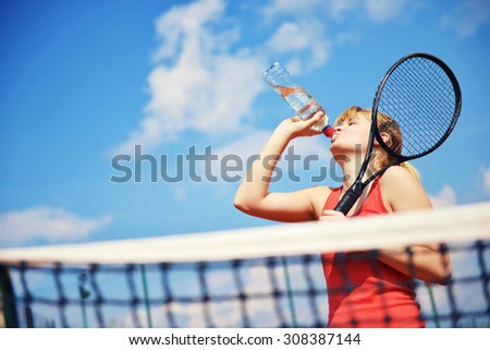 Low angle view of female tennis player drinking a water .Shallow doff, copy space