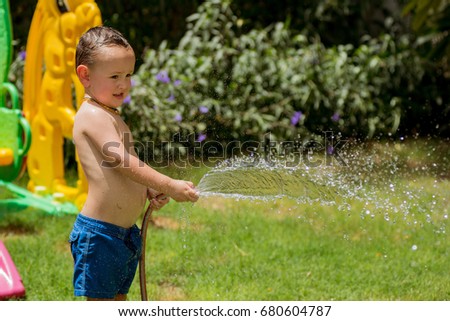 Little boy playing with water in the garden at sunny day