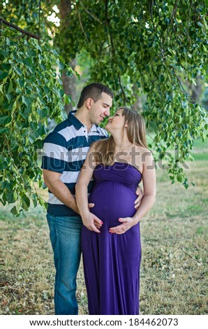 Portrait of a happy, young man touching his pregnant wife's belly