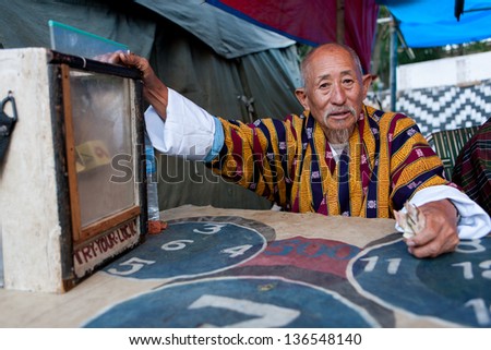 WANGDI,BHUTAN - SEPTEMBER 24:Buthanese man invites people for a game of dice at the Wangdi Festival on September 24,2012 in Wangdi,Bhutan.Gambling is a very popular activity in Bhutan.