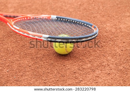 Tennis ball and racket on the clay tennis court