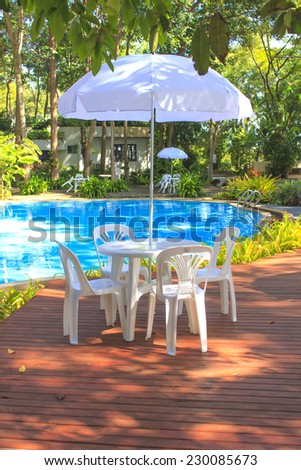 White plastic garden furniture catches the evening beside the pool