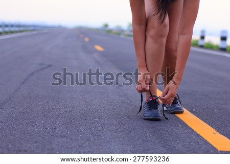 Close up of girl tying her running shoe laces at sunrise