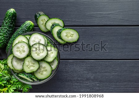 Cucumber on  dark wood texture background.Cucumbers harvest in summer. Cucumbers for salads or canning. Summer vegetables.Slices of fresh cucumbers in a bowl.