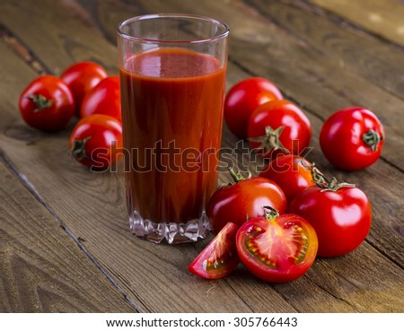 Glass of tomato juice on wooden table, on wood plants background, fresh drink
