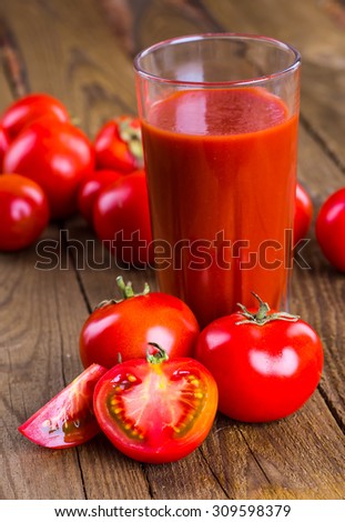 Glass of tomato juice on wooden table, on wood plants background, fresh drink