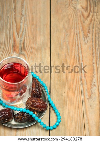 Still life, food and drink, holidays concept. Ramadan dates, tea and beads on a wooden table. Selective focus, copy space background