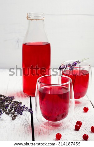 Still life, food and drink, health and homeopathy concept. Cranberry (red berries) drink in glass with lavender on a wooden table. Selective focus