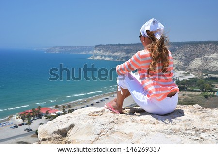 Girl on the rock looking to the ocean. Cyprus