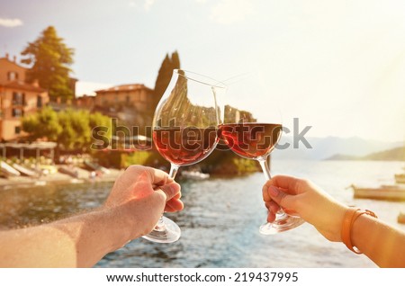 Two wineglasses in the hands. Varenna town at the lake Como, Italy