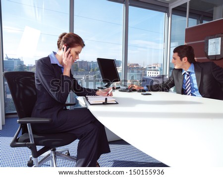 Couple working on laptop computer at office. Woman calling on mobile phone.