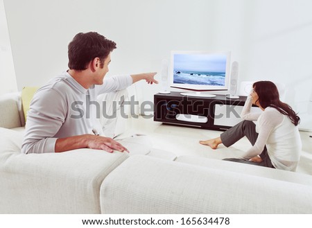 happy couple sitting on sofa and watching television together