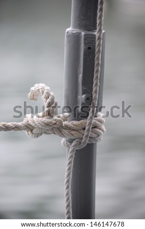 Rope tied off to a post using boating knots blurred ocean water background