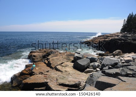 Children waiting on waves to hit the rocky coast of Maine at Schoodic Point