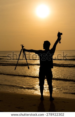 Silhouette of people on a beach.Man holding photography equipment on the beach.