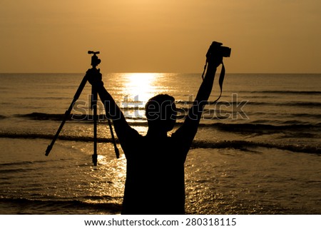 Silhouette of people on a beach.Man holding photography equipment on the beach.