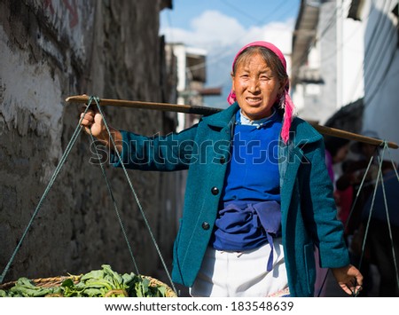 DALI, CHINA - MARCH 24, 2014: Farmers carrying pole walking in Dali Ancient City, Yunnan Province, China.
