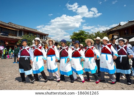 LIJIANG, CHINA - APRIL 7, 2014:  A group of Naxi nationality old women dressed in national clothing dancing. Located in Lijiang Old Town Square Street (Sifang Street), Yunnan Province, China.