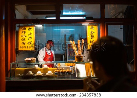 BEIJING, CHINA - OCTOBER 24, 2014: Wangfujing Snack Street at night. Chinese chef making tradition Chinese food. Located in Beijing, China.
